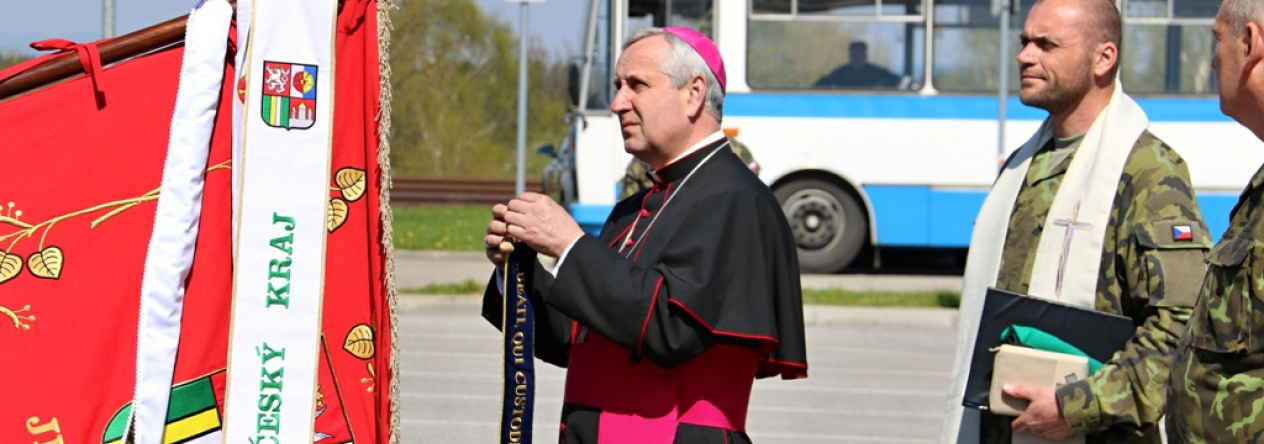 Biskup Kročil připeňuje stuhu na bojový prapor pěší roty AZ